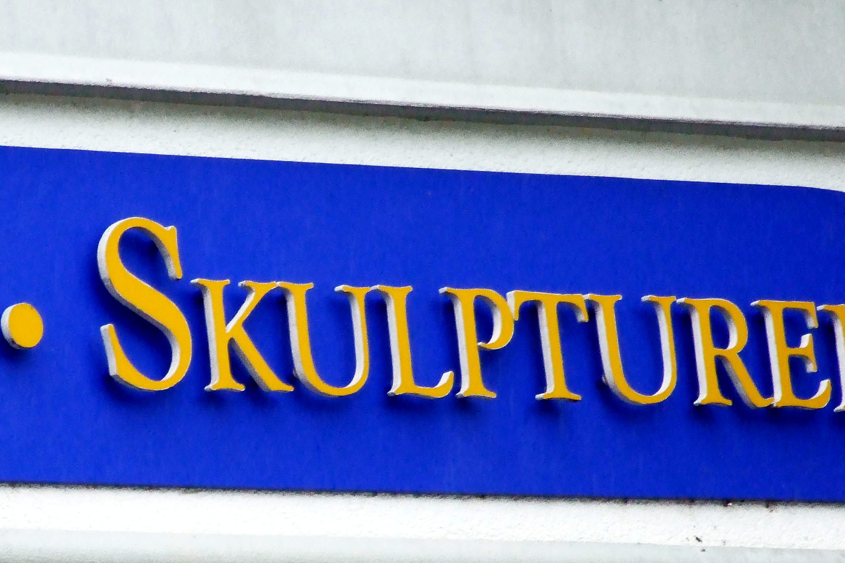 Detail des blauen Fassadenschilds der Walentowski Galerien: die goldenen Buchstaben sind plastisch aufgesetzt und werfen Schatten auf den Schildgrund