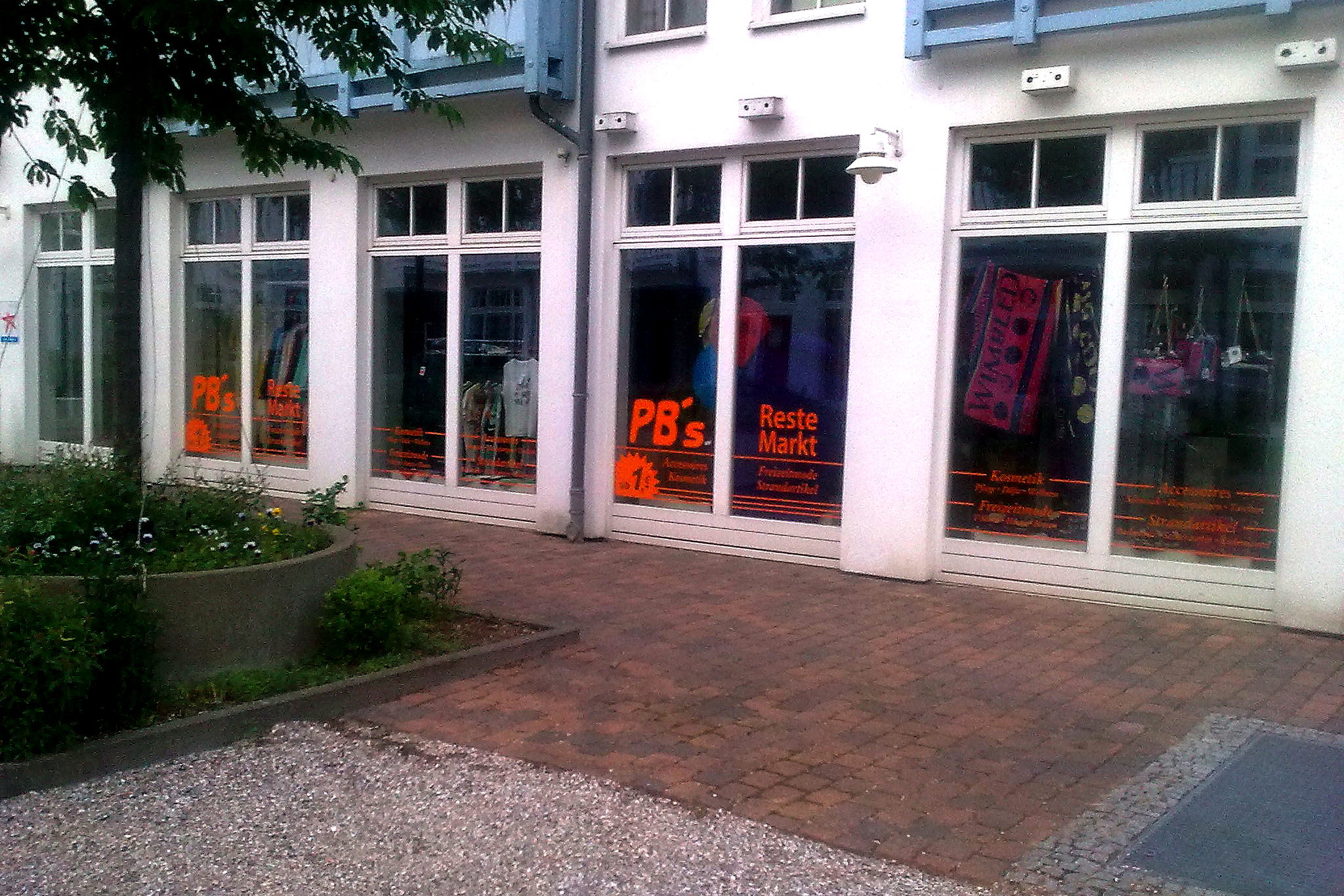 Durchgehendes oranges Schriftband ueber mehrere Schaufensterachsen des PB's Reste Markt