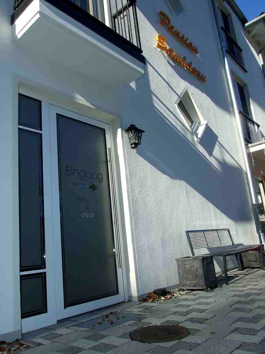 Glastuer der Pension Sanddorn mit Milchglasfolie beschriftet, daneben der orangefarbene Fassadenschriftzug